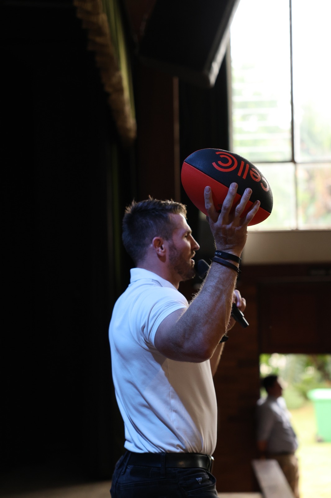 Jaco Kriel on stage holding up a Cell C rugby ball while speaking into a microphone