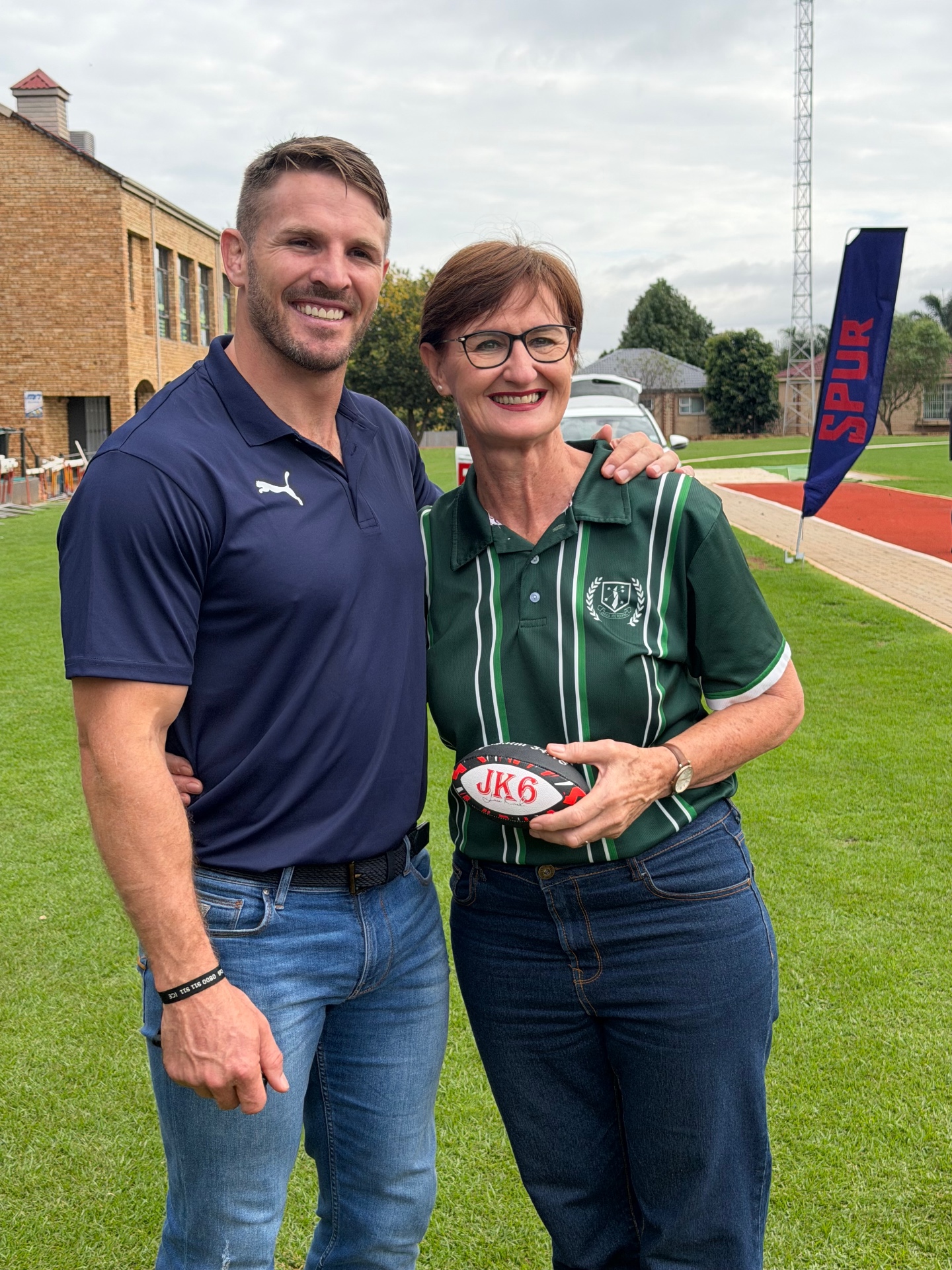 Jaco Kriel with a school principal holding a signed JK6 rugby ball